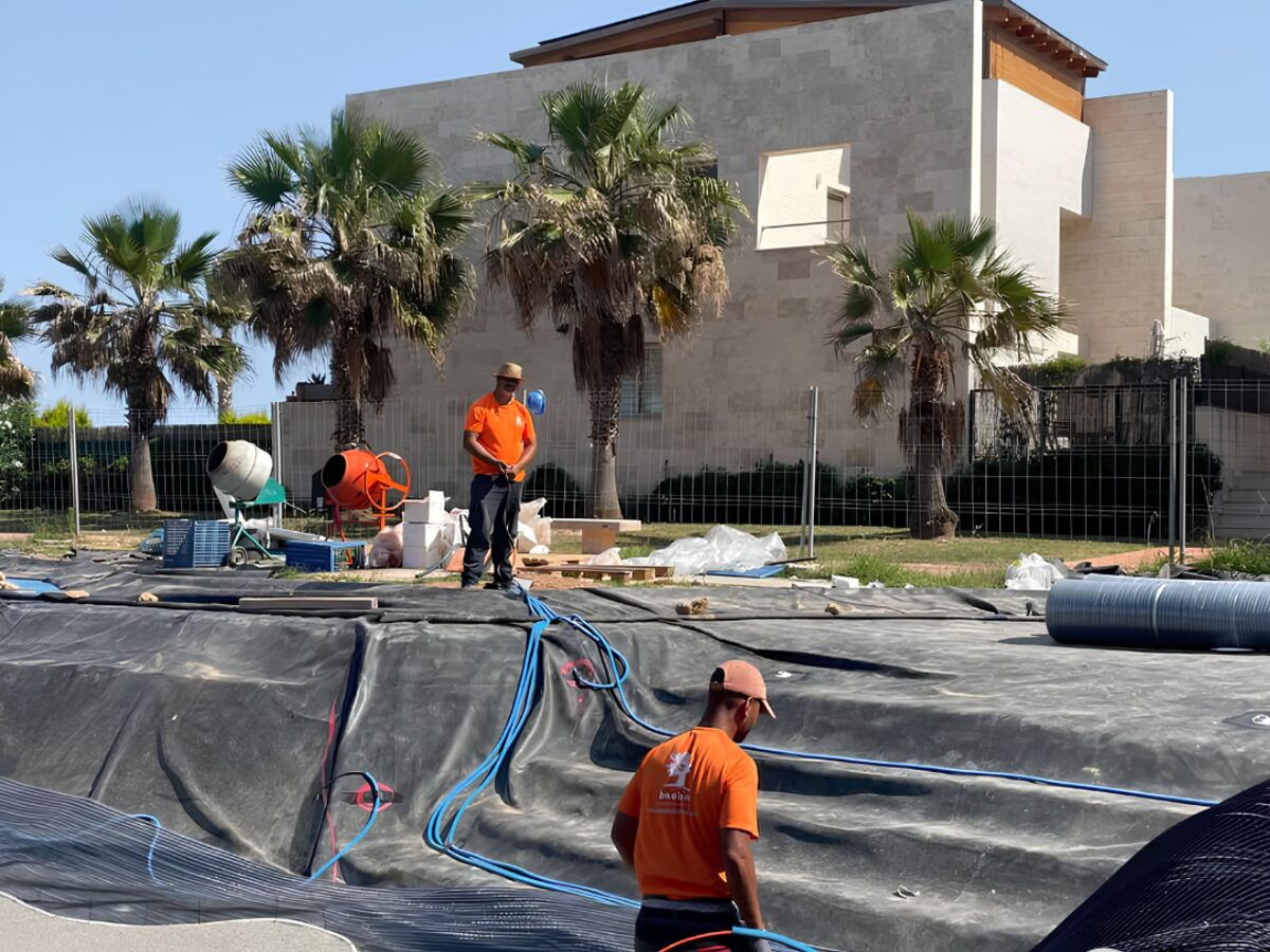 Crew laying protective fabric and liner over the excavated pool shape