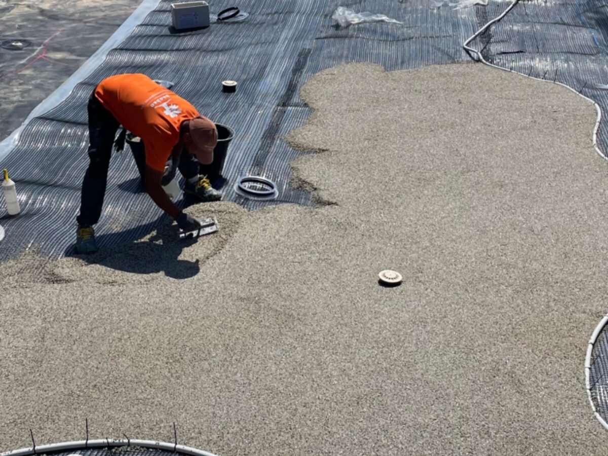 Installer working over the first reinforcement mesh as the coat goes on