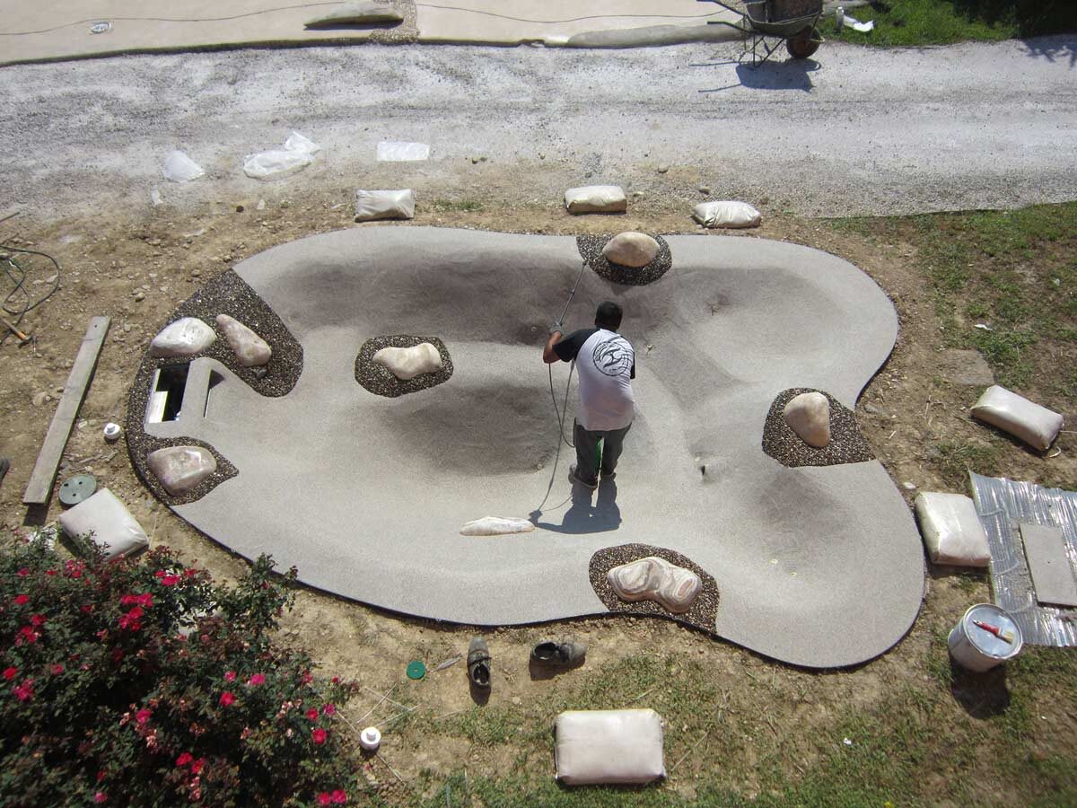 Structural resin and quartz coat spread across the pool floor