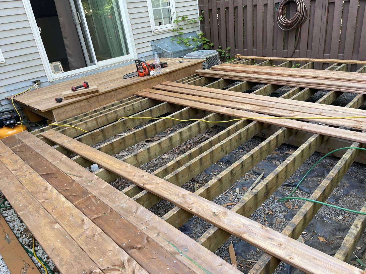 an early stage of a wooden deck construction, with the framework of laid out joists with already installed deck boards
