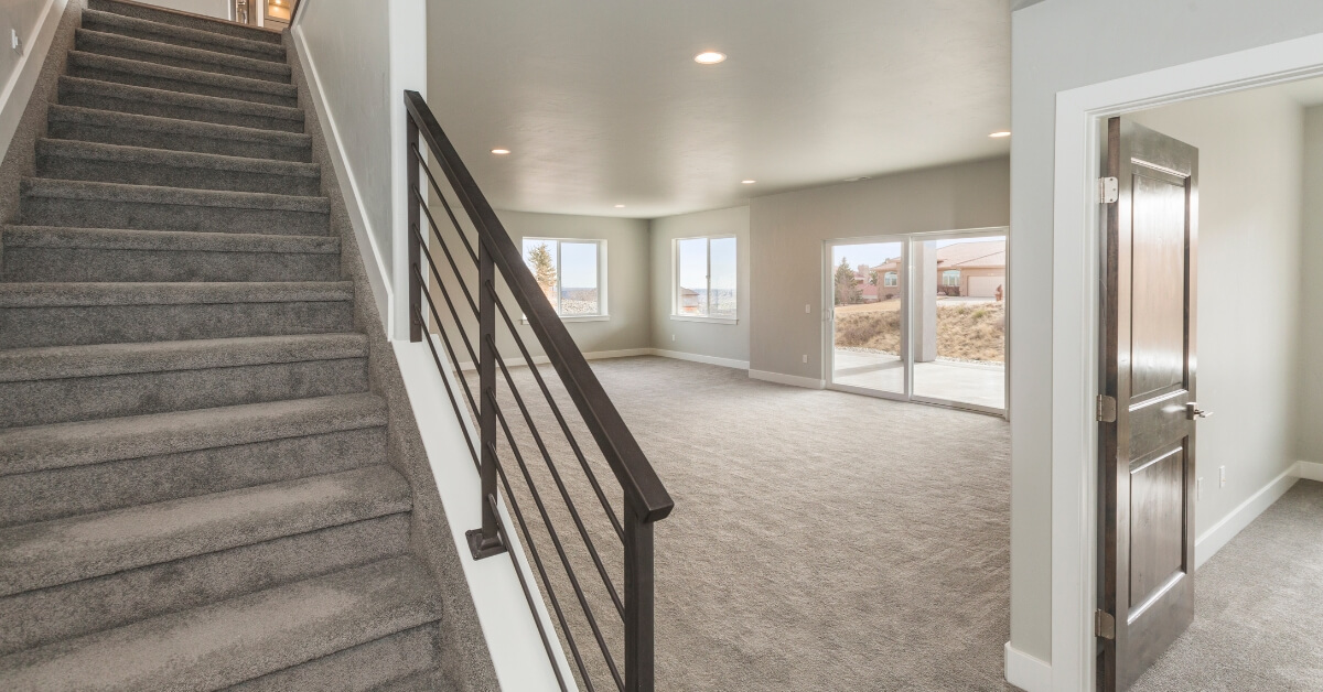 Spacious basement area under renovation in Ottawa, showcasing new plush carpeting and a contemporary metal staircase railing