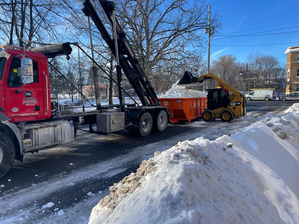 A coordinated snow removal effort is taking place on a sunny day, illustrating a proactive approach to managing winter conditions in an urban setting.