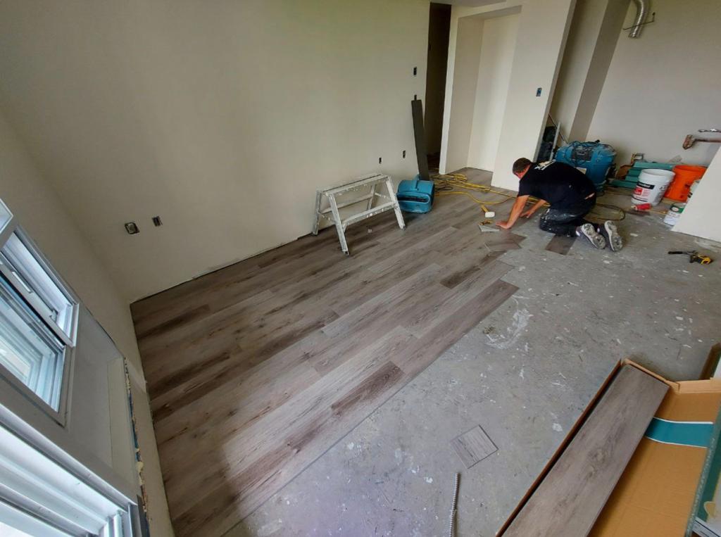 interior demolition, where a worker is focused on disassembling the flooring in a room that's being prepared for renovation