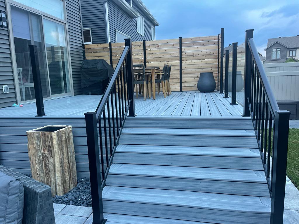 contemporary garden deck installation featuring a smooth, grey-toned wooden flooring with a sleek black railing system