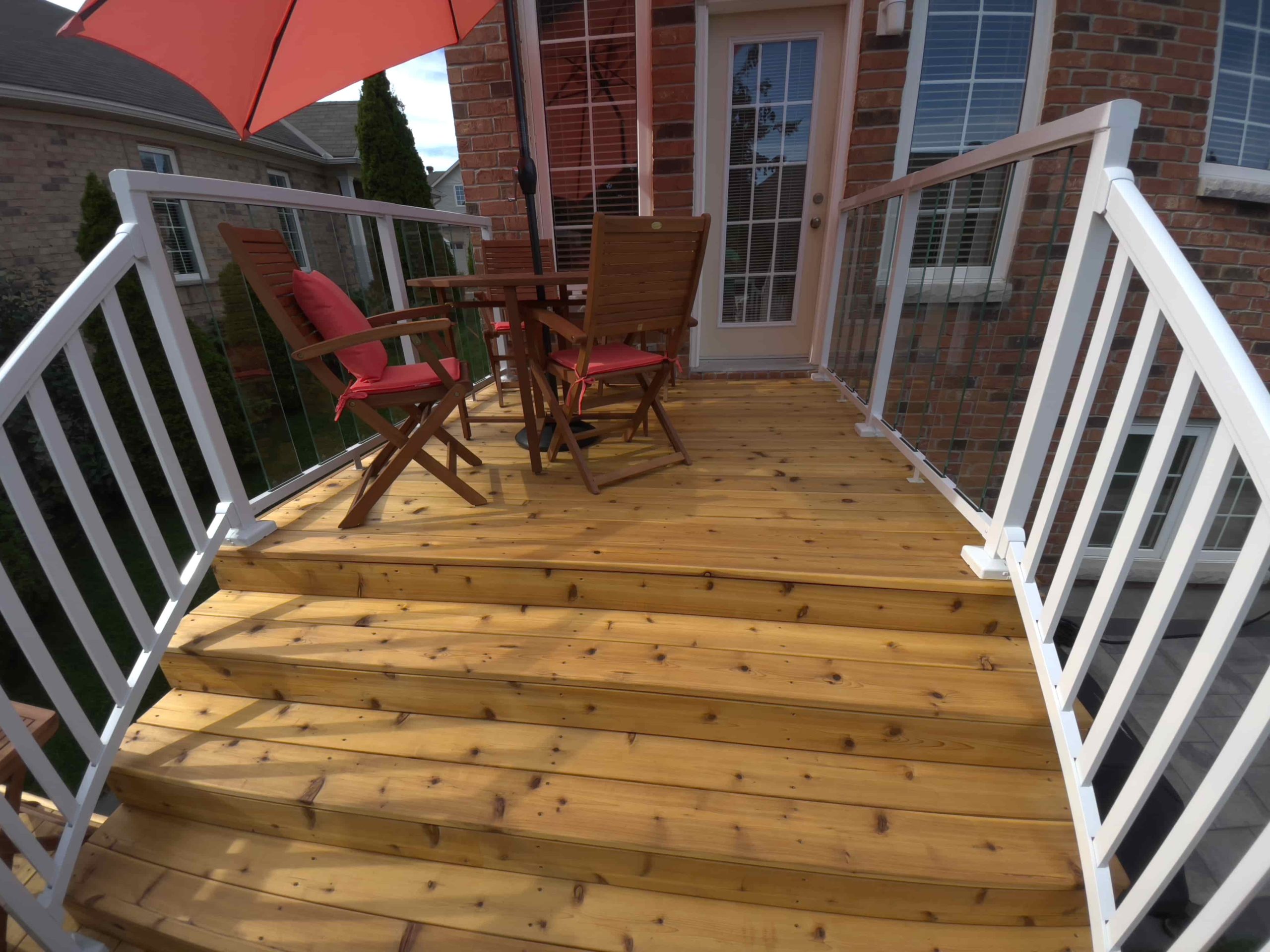 A cozy wooden deck boasts a stylish white railing, offering a perfect spot for outdoor relaxation