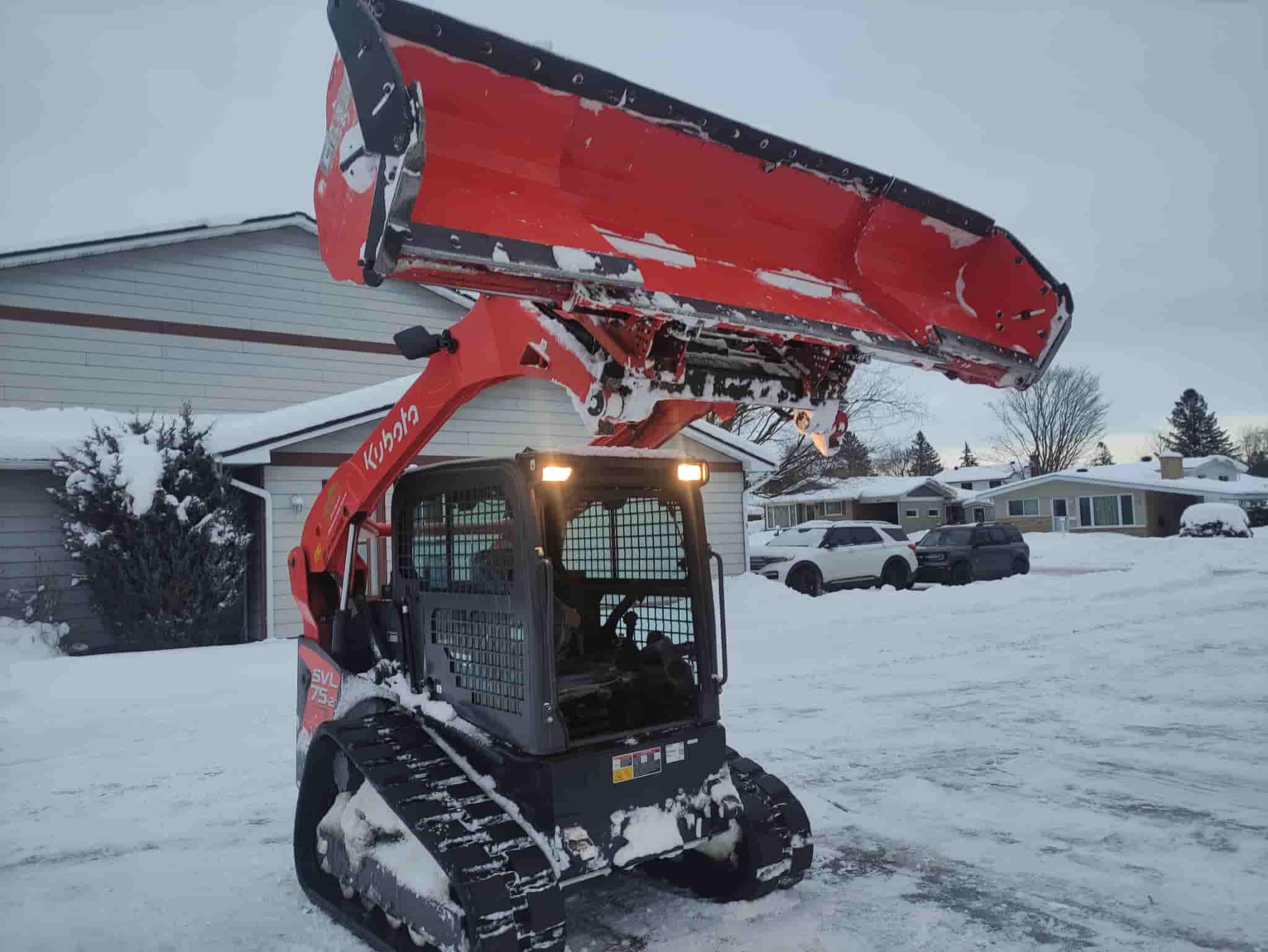 A Kubota compact track loader equipped with a snowblower attachment actively removes snow, showcasing efficient snow clearing services in Ottawa during winter.