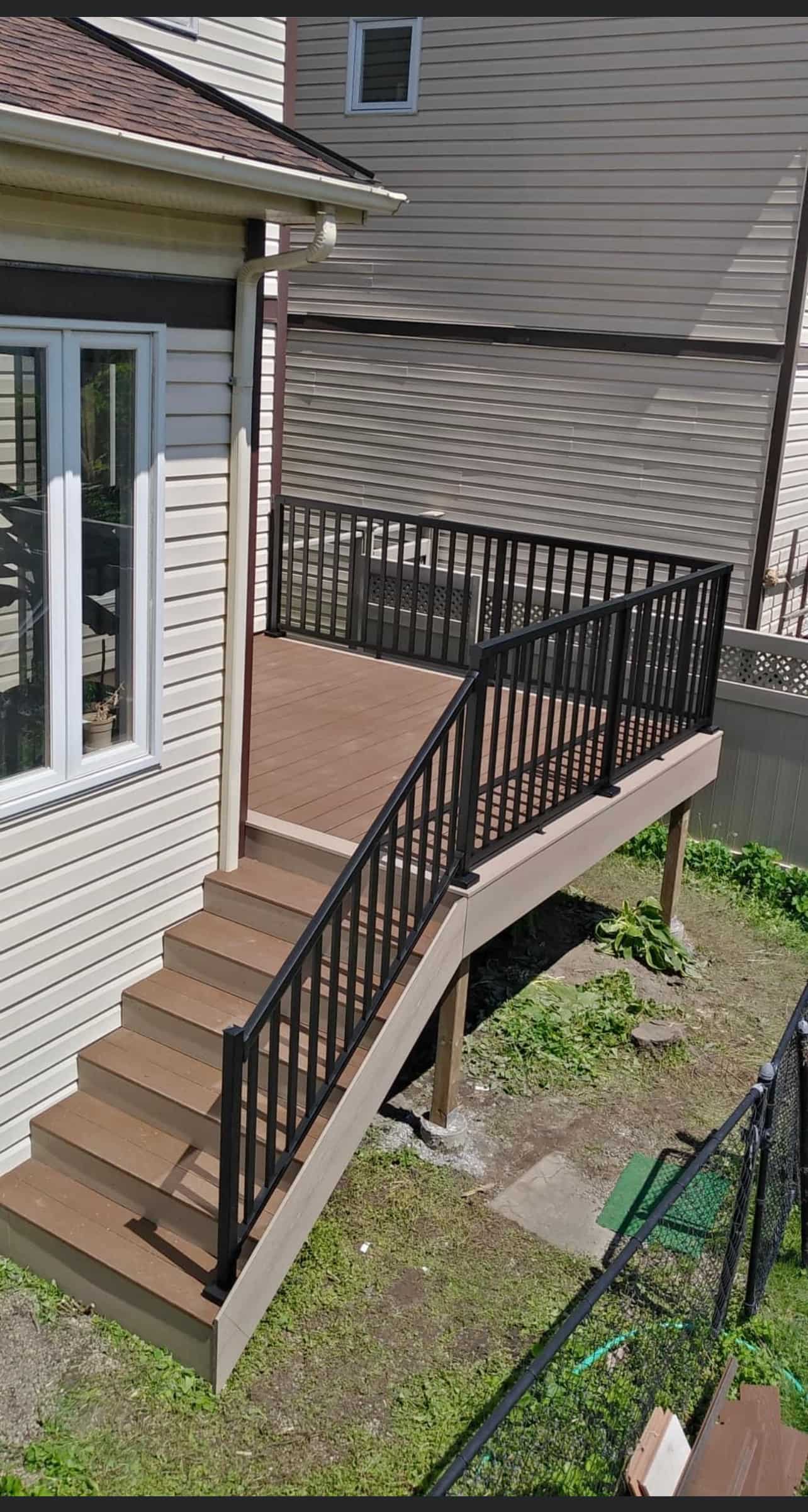 A newly constructed elevated deck with a modern integrated railing system enhances this home's outdoor space, featuring steps leading down to a lush garden area.