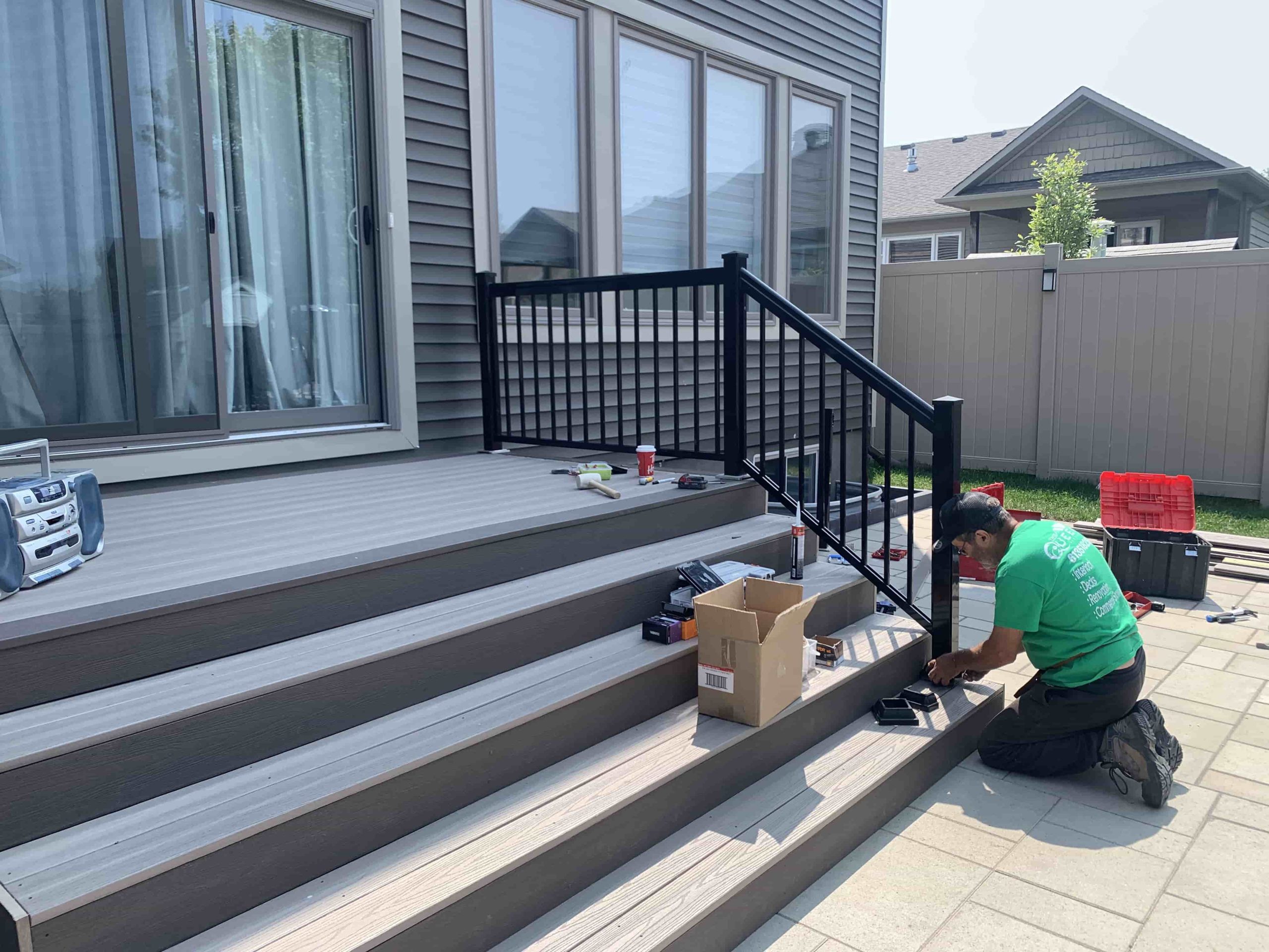 A skilled worker is meticulously installing a modern deck at a residential home, showcasing the process of enhancing outdoor living spaces with durable and stylish materials.