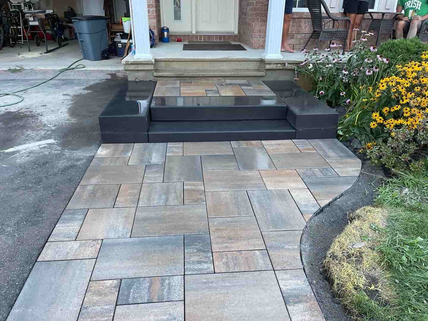 A front walkway featuring meticulously installed interlocking tiles leading to a house entrance.