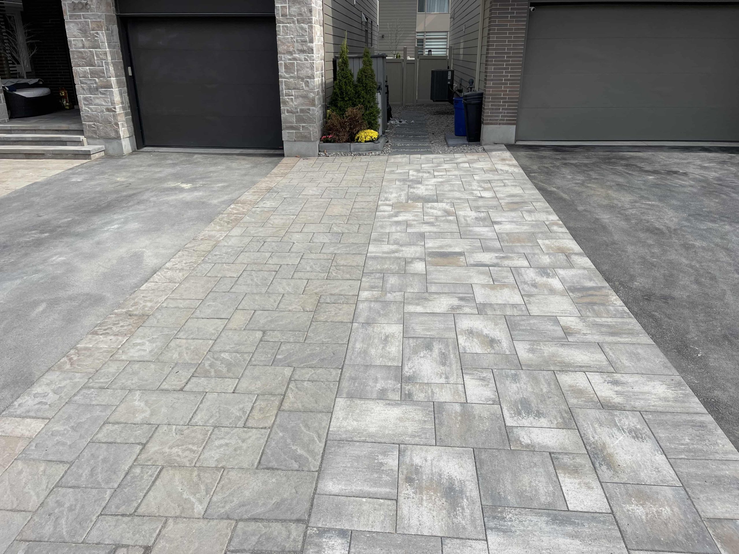 This image shows a driveway at an urban residence with precision-installed interlocking tiles that transition into an asphalt section.