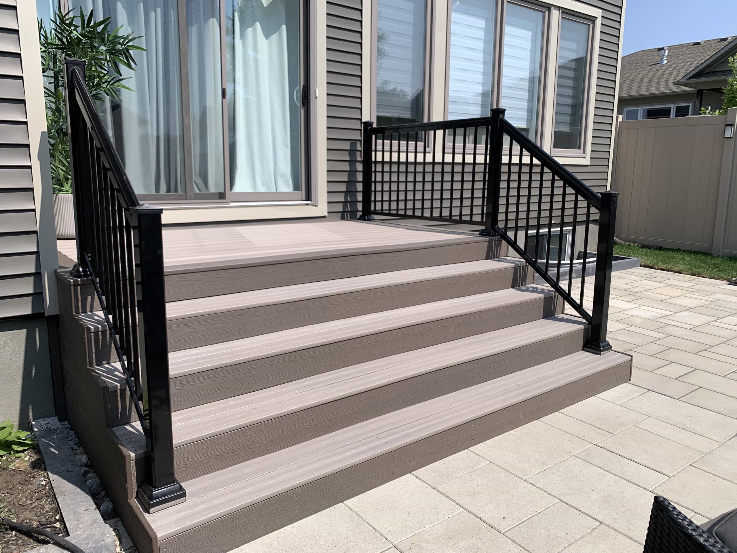A newly installed deck with elegant railings enhances a residential backyard, highlighting the precise workmanship and contemporary design that adds to the home's outdoor appeal